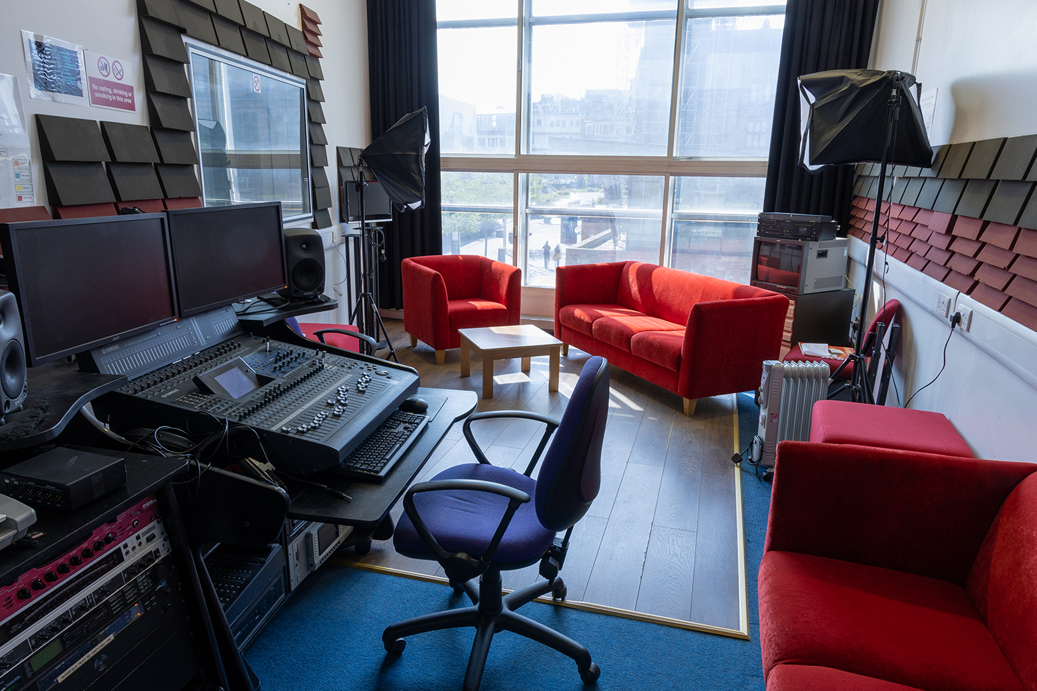 A recording studio with a sound desk, sofas and padded walls